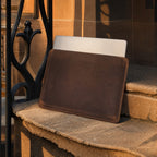 The leather laptop sleeve on a sunlit brownstone step with a laptop part way out