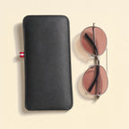 The pouch laid flat with a folded pair of sunglasses beside it