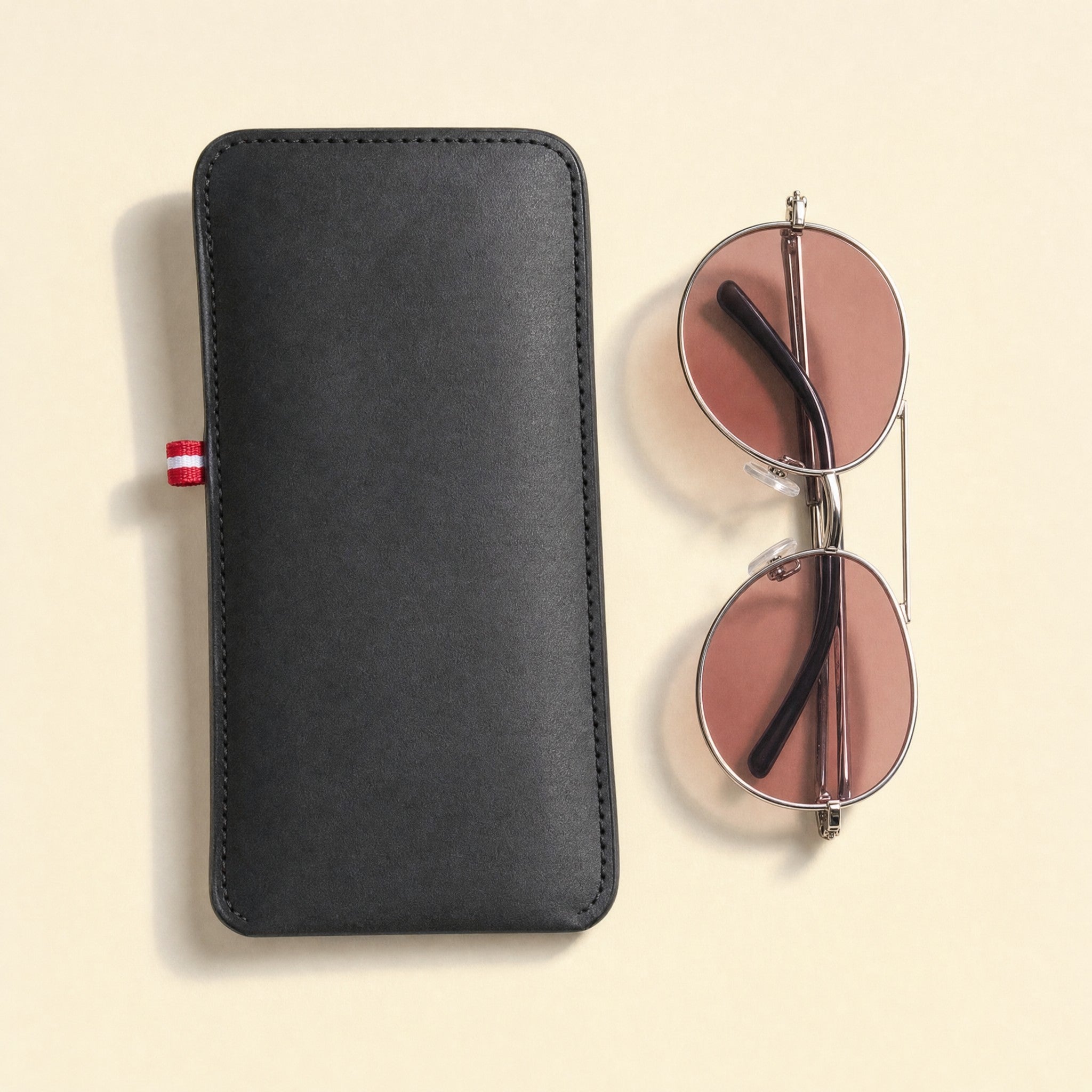The pouch laid flat with a folded pair of sunglasses beside it